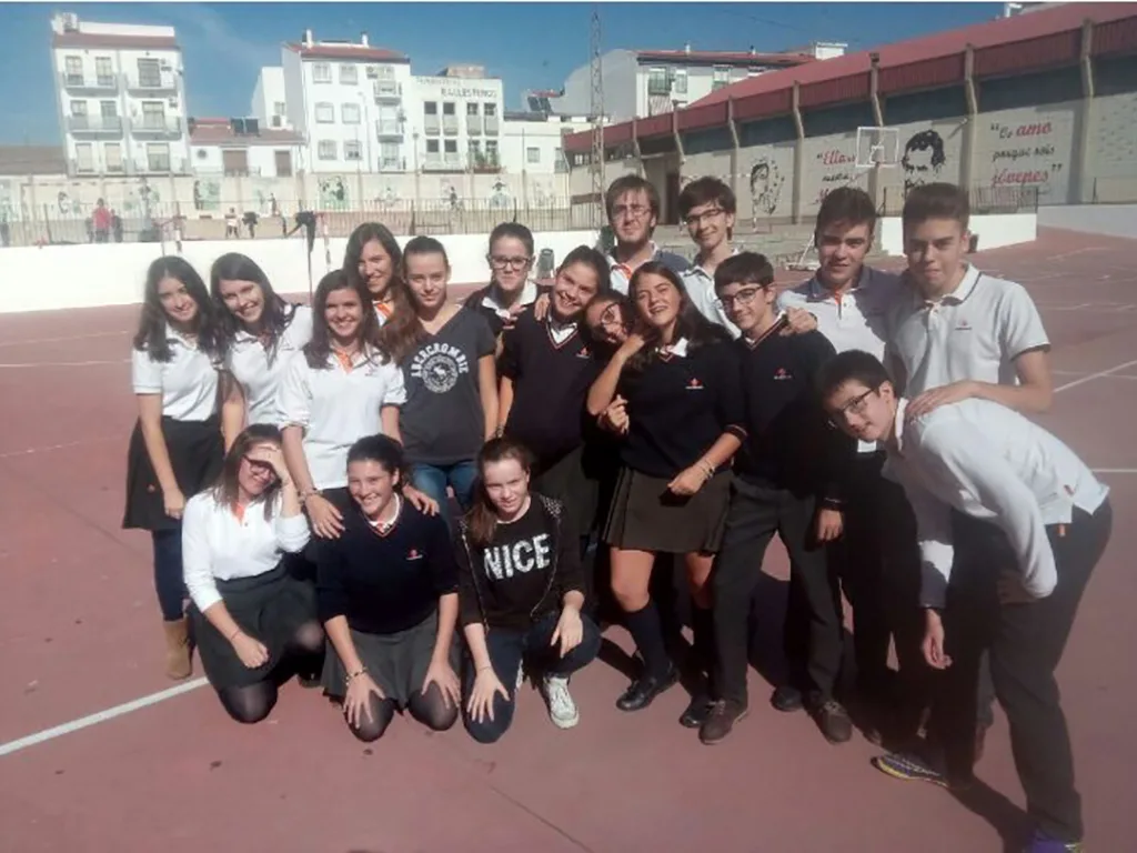 Gruppenfoto auf einem Schulhof, dahinter Wohnhäuser.